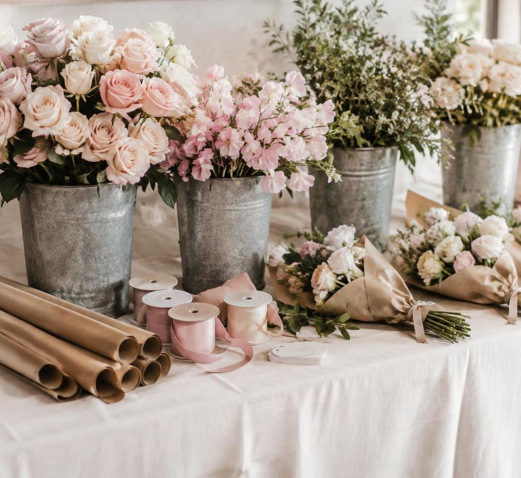 A linen table of loose roses and sweet peas with kraft wrap and silk ribbon